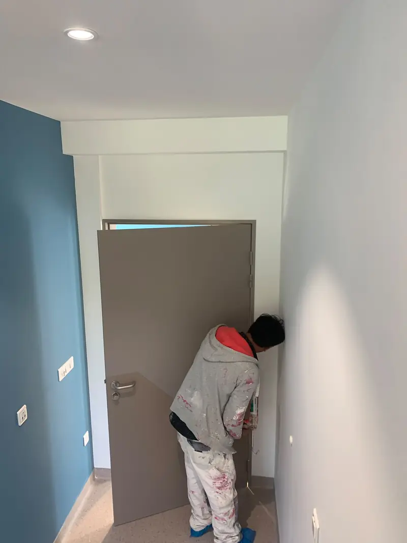 Peintre travaillant sur une porte et un mur bleu