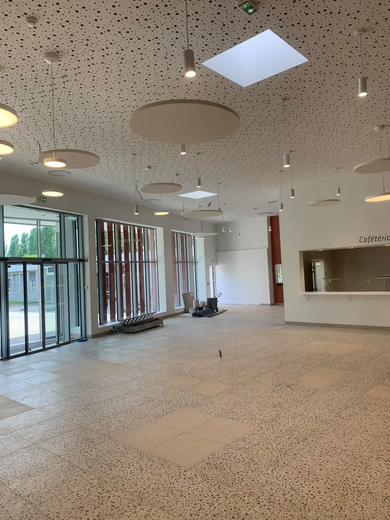 Grande salle rénovée avec plafond acoustique, sol clair et baies vitrées